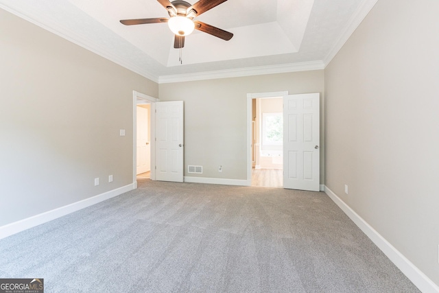 unfurnished bedroom with connected bathroom, crown molding, ceiling fan, a raised ceiling, and light colored carpet