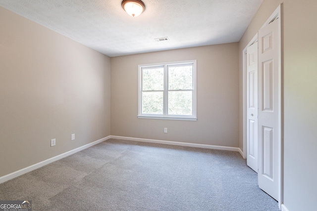 carpeted spare room with a textured ceiling