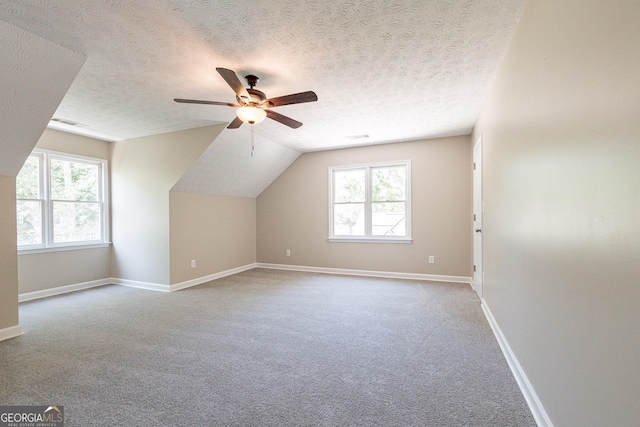 bonus room with ceiling fan, light colored carpet, vaulted ceiling, and a textured ceiling