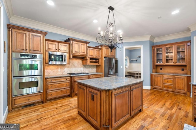 kitchen featuring light hardwood / wood-style floors, decorative light fixtures, appliances with stainless steel finishes, and a center island