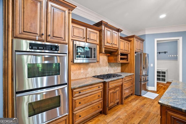 kitchen featuring stone countertops, appliances with stainless steel finishes, tasteful backsplash, light hardwood / wood-style flooring, and crown molding