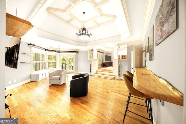 living room with a raised ceiling, light wood-type flooring, french doors, and ornamental molding