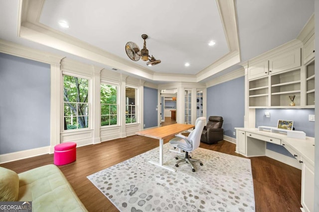 office space with dark wood-type flooring, crown molding, and a tray ceiling