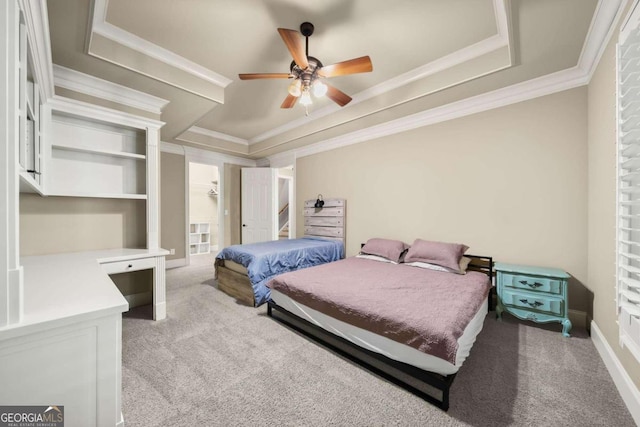 carpeted bedroom with ceiling fan, crown molding, and a tray ceiling