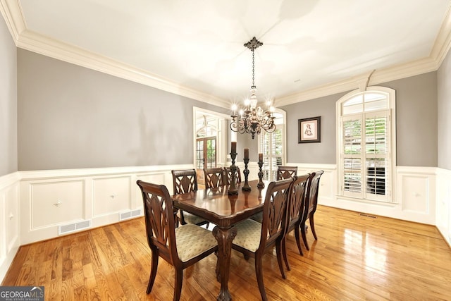 dining room featuring light hardwood / wood-style flooring, a chandelier, and crown molding