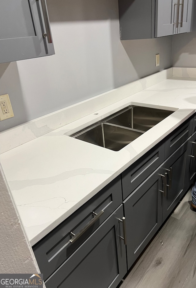 kitchen with light stone countertops, sink, and light hardwood / wood-style floors