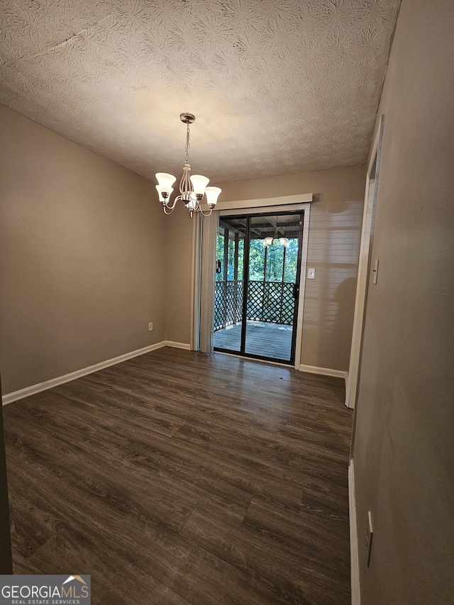 unfurnished dining area featuring dark hardwood / wood-style floors, a textured ceiling, and an inviting chandelier