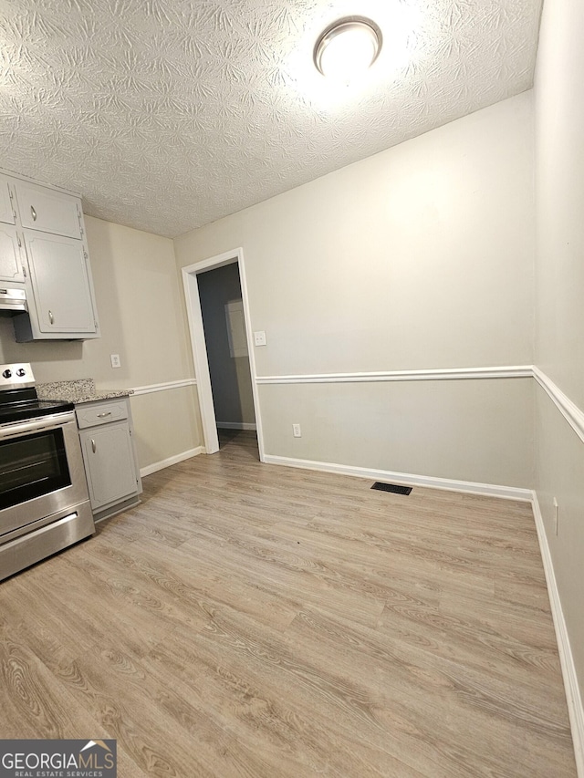 kitchen featuring a textured ceiling, electric range, and light hardwood / wood-style floors