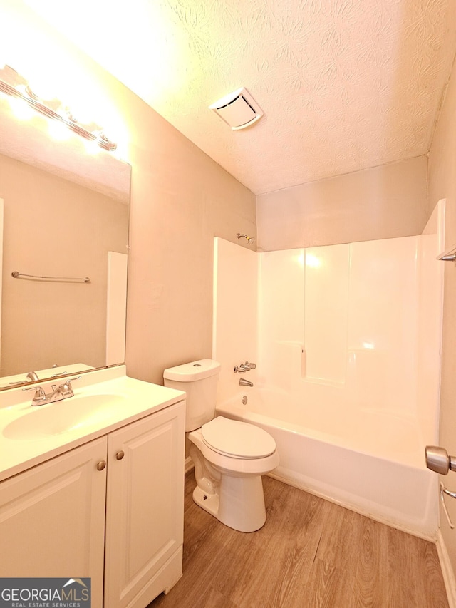 full bathroom with vanity, wood-type flooring, a textured ceiling, and toilet