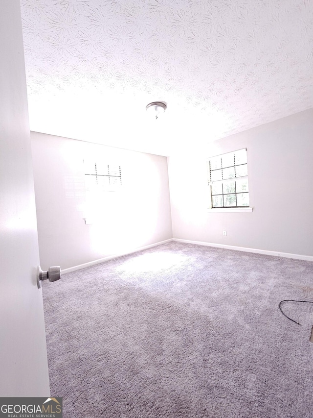 carpeted empty room featuring a textured ceiling