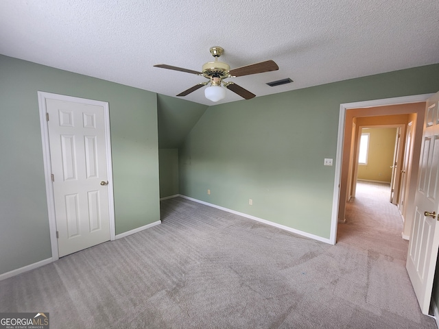 unfurnished bedroom featuring ceiling fan, carpet flooring, a textured ceiling, and vaulted ceiling