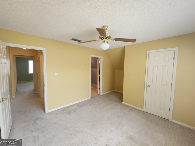 unfurnished bedroom featuring light carpet, a textured ceiling, a closet, and ceiling fan