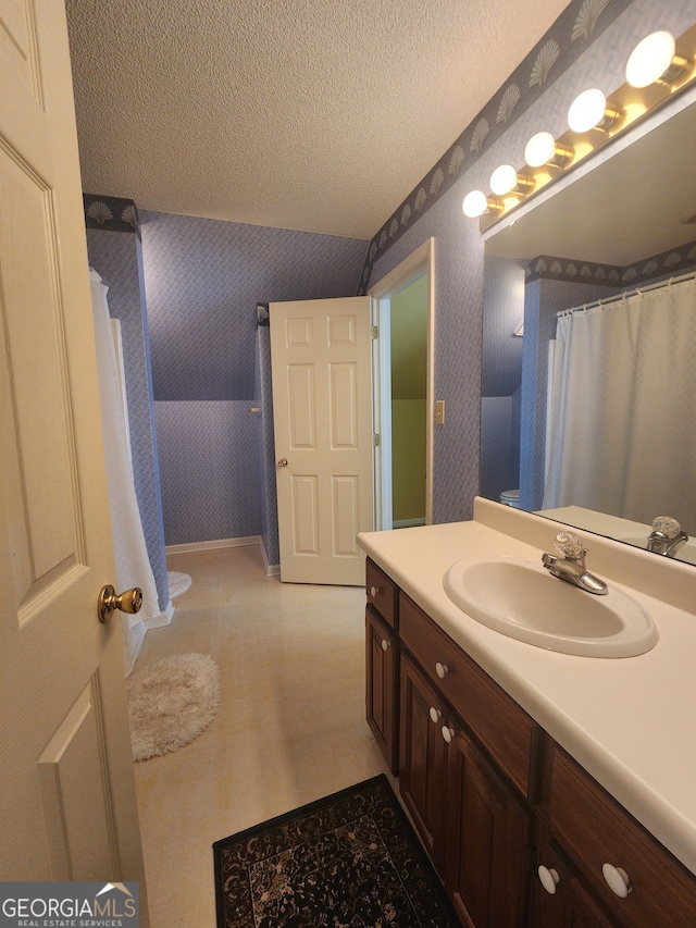 bathroom featuring a textured ceiling, tile patterned floors, vanity, and vaulted ceiling