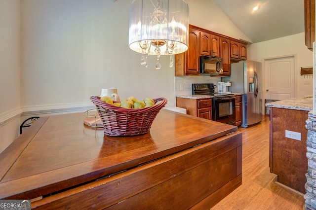 kitchen with light hardwood / wood-style flooring, an inviting chandelier, lofted ceiling, black appliances, and decorative backsplash