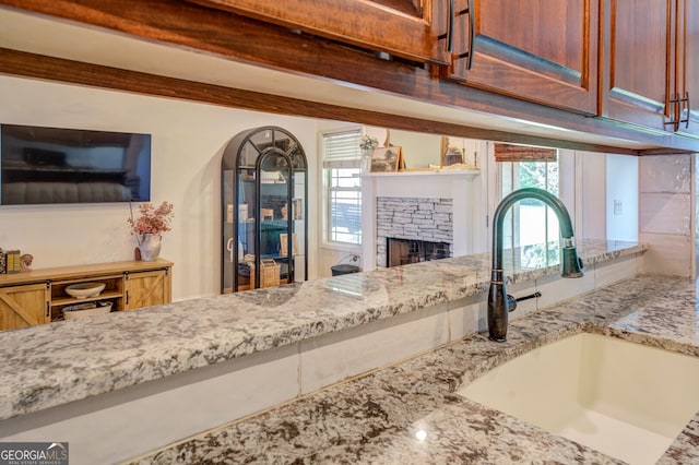 kitchen featuring a stone fireplace, light stone counters, and sink