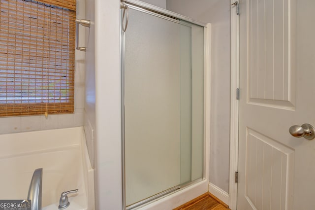 bathroom with hardwood / wood-style flooring and separate shower and tub