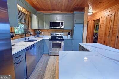 kitchen featuring appliances with stainless steel finishes, sink, light stone counters, and wooden ceiling