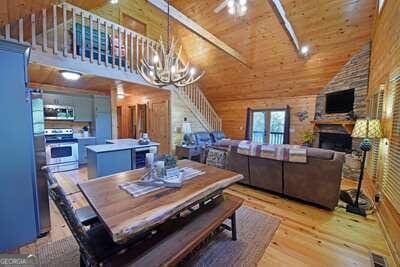 dining area featuring light wood-type flooring, high vaulted ceiling, wood walls, wooden ceiling, and a chandelier