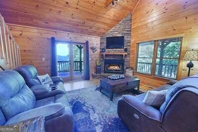 living room with wood walls, high vaulted ceiling, a stone fireplace, and wood ceiling