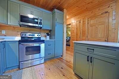 kitchen with light wood-type flooring, stainless steel appliances, wooden walls, and wood ceiling