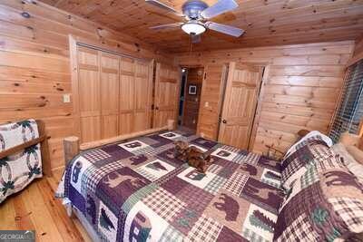 bedroom with hardwood / wood-style floors, wood walls, ceiling fan, and wooden ceiling