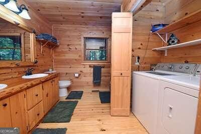 washroom with light wood-type flooring, wooden ceiling, wooden walls, and sink