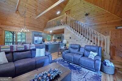 living room with high vaulted ceiling, a notable chandelier, wood-type flooring, wood walls, and wood ceiling