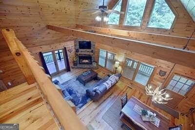 living room with high vaulted ceiling, a stone fireplace, hardwood / wood-style floors, and a wealth of natural light