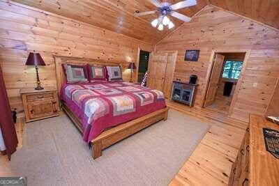 bedroom featuring wood walls, hardwood / wood-style flooring, ceiling fan, and lofted ceiling