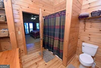 bathroom featuring ceiling fan, toilet, wood walls, and wood-type flooring