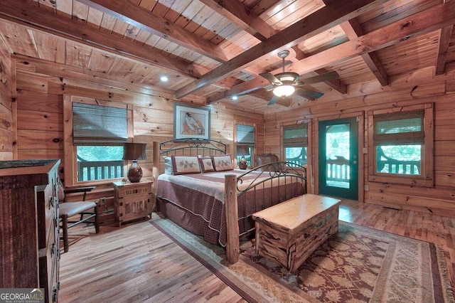 bedroom with beam ceiling, light wood-type flooring, wood ceiling, and wood walls