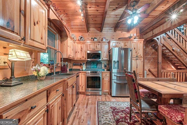 kitchen with sink, rail lighting, appliances with stainless steel finishes, beamed ceiling, and light hardwood / wood-style floors