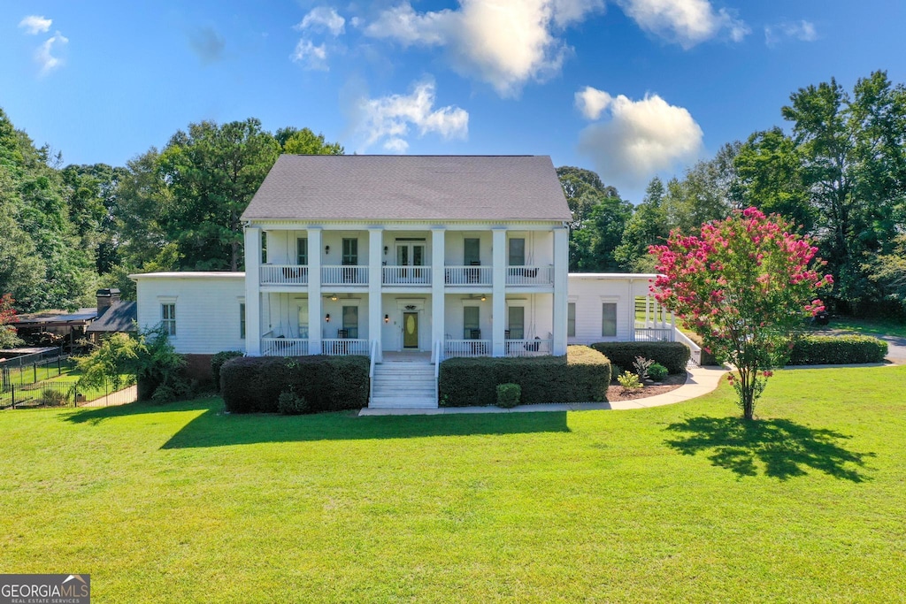 view of front facade featuring covered porch, a balcony, and a front yard