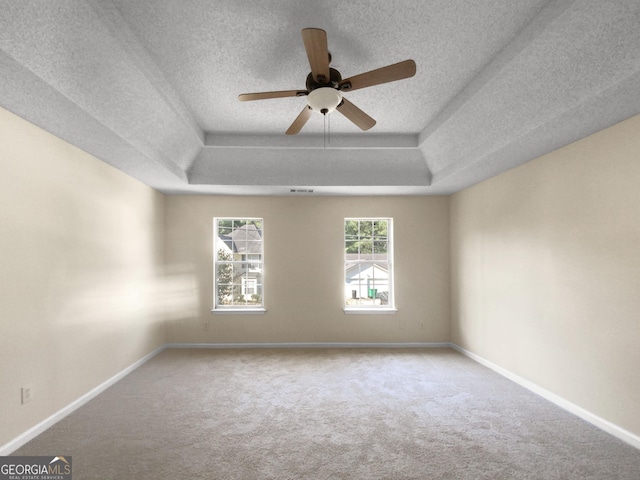 empty room with a raised ceiling, baseboards, and carpet floors