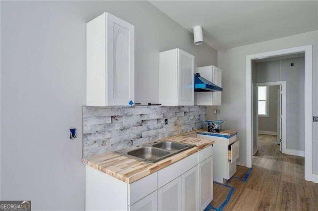 kitchen with sink, tasteful backsplash, butcher block countertops, and white cabinets