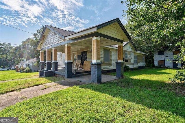 view of side of home featuring covered porch and a yard