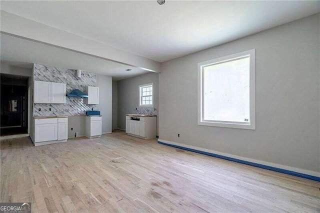 kitchen featuring light hardwood / wood-style floors, white cabinets, and backsplash