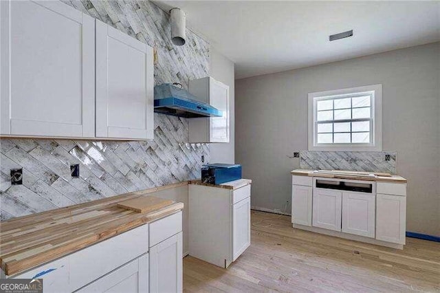 kitchen featuring backsplash, white cabinets, butcher block counters, and light hardwood / wood-style flooring