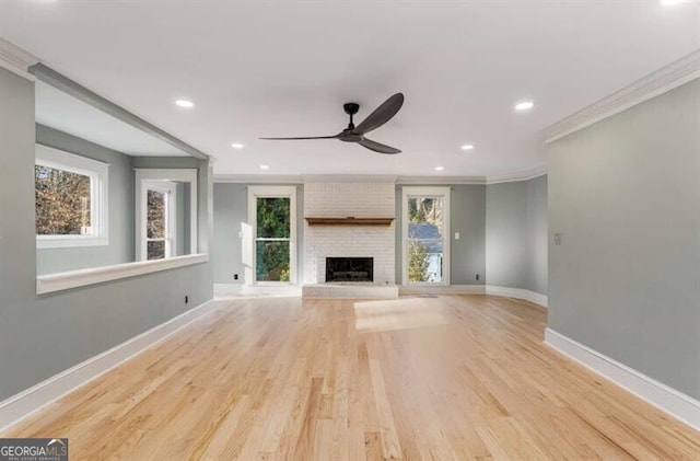 unfurnished living room with a fireplace, recessed lighting, light wood-style flooring, ornamental molding, and baseboards