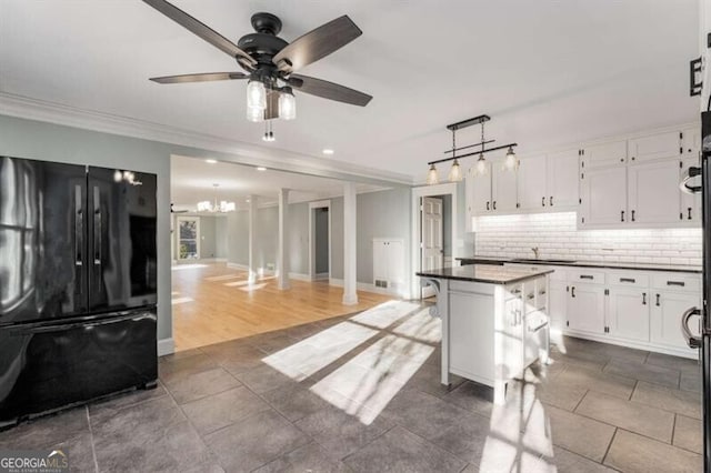 kitchen featuring white cabinets, ornamental molding, freestanding refrigerator, tasteful backsplash, and dark countertops