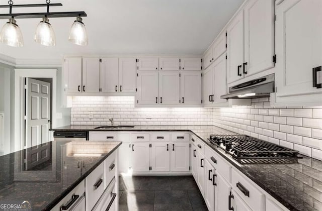 kitchen featuring under cabinet range hood, white cabinets, and dark stone countertops