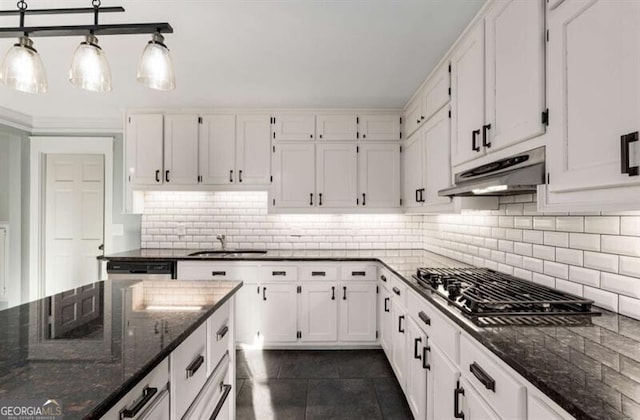 kitchen featuring backsplash, white cabinets, under cabinet range hood, and dark stone countertops