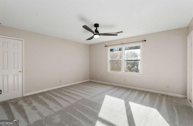 carpeted spare room featuring visible vents, baseboards, and ceiling fan