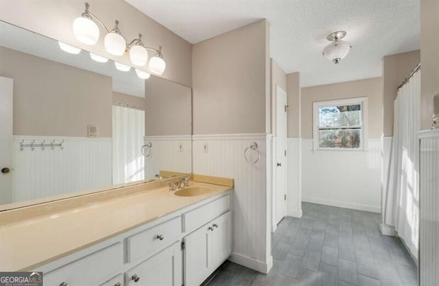 bathroom with a textured ceiling, wainscoting, and vanity