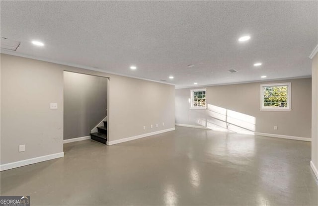 below grade area featuring a textured ceiling, stairway, recessed lighting, and baseboards