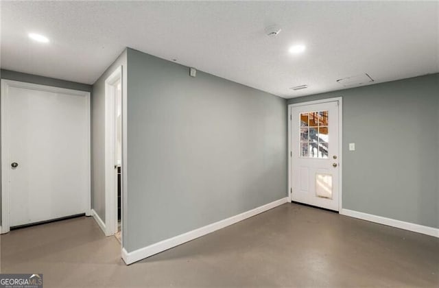 foyer entrance with finished concrete floors, recessed lighting, a textured ceiling, and baseboards