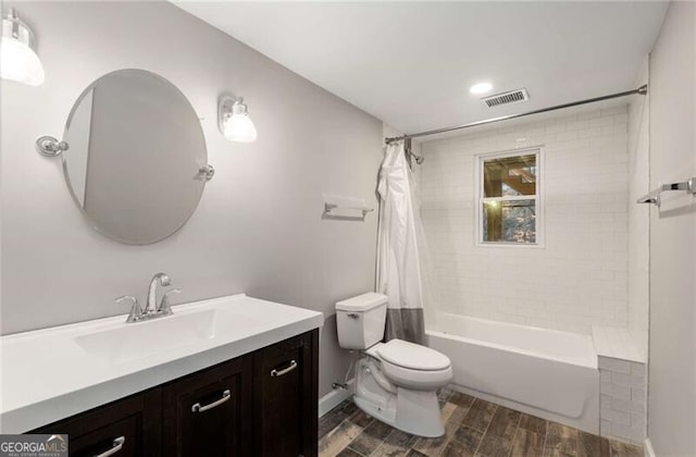 bathroom featuring wood finish floors, visible vents, shower / bathtub combination with curtain, toilet, and vanity