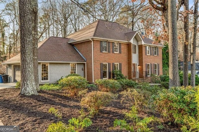 colonial inspired home with driveway, brick siding, and an attached garage