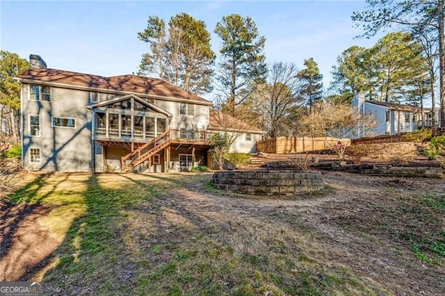 back of house featuring a chimney, a sunroom, fence, a deck, and stairs