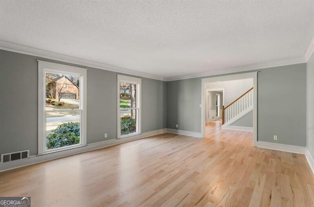 empty room featuring light wood finished floors, stairs, and a textured ceiling